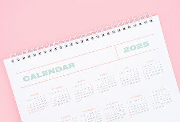 White calendar 2025 on pink background close-up, planning concept.