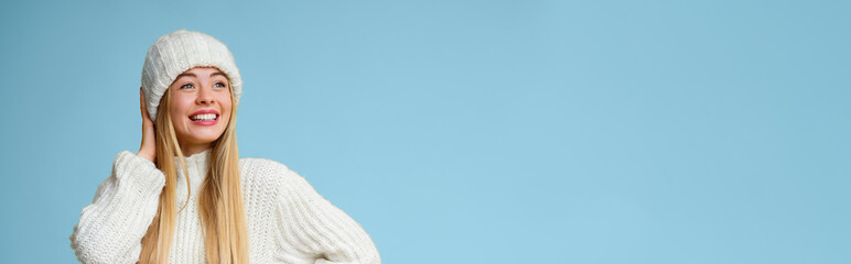 Excited blonde woman in winter hat looking at empty space over yellow background, panorama