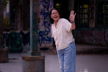 A woman standing on a train platform was waving her hand to one side; smiling, happy expression