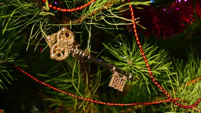 Golden key. Christmas tree, toy decorations. New Year and Merry Christmas. Smooth camera movement on the slider. Video postcard. Live christmas tree with garlands and toys. Realtor greetings, realty