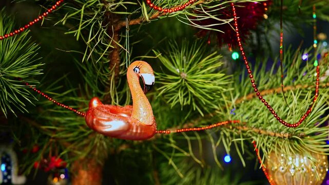 Pink flamingo. Christmas tree, toy decorations. New Year and Merry Christmas. Smooth camera movement on the slider. Video postcard. Live christmas tree with garlands and toys