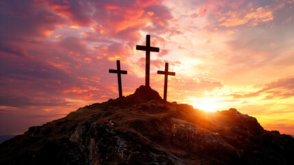 Three crosses on a hill against a vibrant sunset.