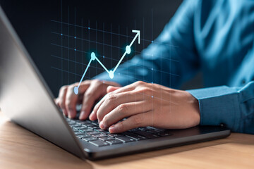 chart, financial, rate, finance, analysis, growth, graph, strategy, stock, invest. A person is typing on a laptop with a graph of a line going up. Scene is focused and determined.