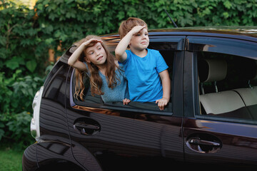 Children in the car window have fun, laugh, rejoice.