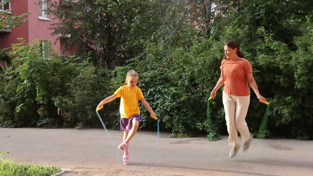 mom and child daughter jumping  over a rope in the yard near the house
