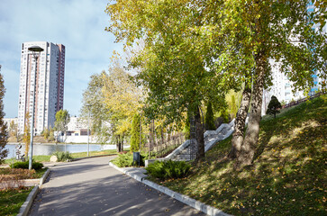 Walkway surrounded by trees and lawns in Kyiv, Europe. Recreation place in the autumn city park