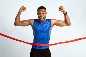 Winner. Excited black sportsman running, crossing the finish line breaking the tape, yellow studio background