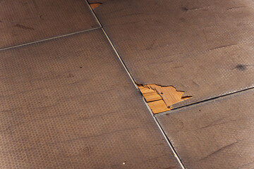 Old floor covering with holes on a wooden plywood base
