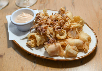 Una ración de calamares fritos con salsa de ajo en un restaurante europeo.