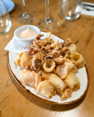 Una ración de calamares fritos con salsa de ajo en un restaurante europeo.