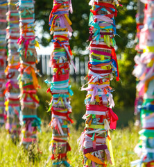 Multicolored ribbons hang on wooden poles. Religion