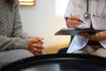 Professional psychiatrist taking note during a counseling session in her clinic. Mental health concept