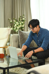 Handsome young businessman sitting on sofa working with laptop computer