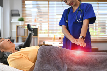 Fototapeta premium Mature woman undergoing alternative therapy treatment, therapist hands over woman stomach. Reiki technique concept