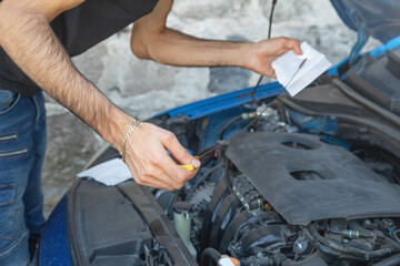 Man checking level of oil in car engine.