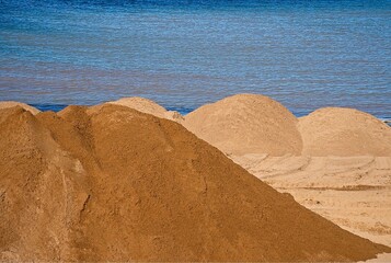 sand dunes ready to be spread on the beach by heavy machinery