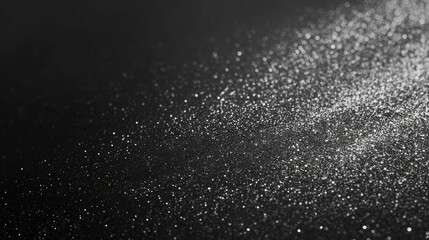 Obraz premium A mesmerizing sprinkle of silver glitter on a dark surface, creating a dreamy, cosmic effect.