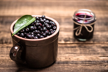 Aronia jam and fresh berry on wooden table.