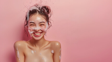 Joyful woman enjoying a refreshing bubble bath with soap on her face and a smile, against a vibrant pink background.