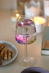 Plate of pastel macarons, cookies and chocolate, cup of tea of coffee, glass of bubble water, various berries, books and accessories on the table. Selective focus, pastel colors.