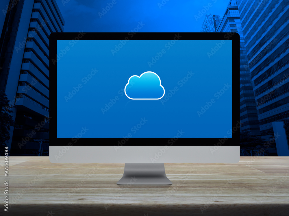 Poster cloud computing icon on desktop modern computer monitor screen on wooden table over office city towe