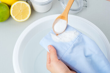Female hands showing sprinkled with soda baking cosmetic stains on the blue clothes in a plastic...