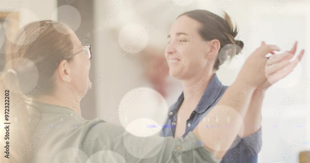 Sticker Animation of white spots of light over caucasian female gay couple dancing in background