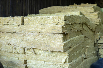 Bales of insulation material stored in a wooden barn during daylight hours