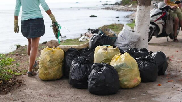 Volunteers throw trash into bags.
