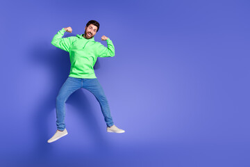 Full length photo of handsome young guy flexing show muscles dressed stylish green garment isolated on violet color background