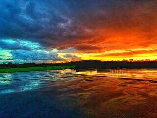 Vibrant sunset with dramatic clouds reflecting on a wet surface.