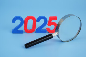 Experts analytics and prognosis for year 2025. Magnifying glass and numbers 2025 on blue background.