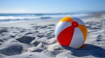 Naklejka premium Vibrant beach ball on sand with the sea in the background