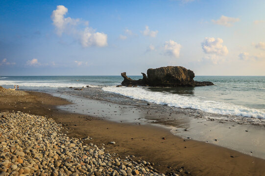 Serene coastal view of El Tunco in El Salvador featuring a rocky outcrop and gentle waves at sunset