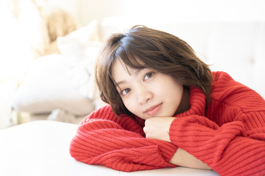赤いニットを着てこちらを見ている女性
