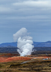 A large cloud of steam rises from a geothermal power plant in the distance. Reykjanes power station