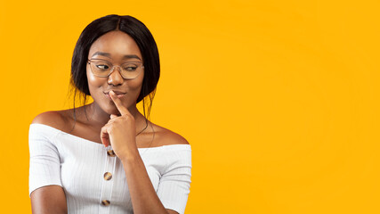 Sly Look. Pretty Afro Girl Thinking About Something Standing Over Orange Studio Background. Panorama, Copy Space