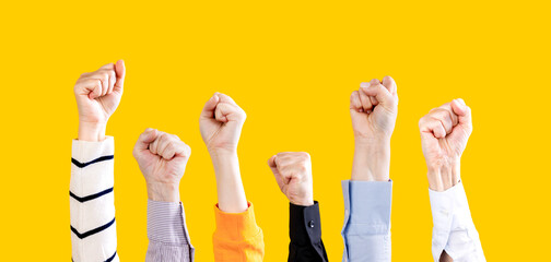 Fototapeta premium Group of activists raising their fists in the air. Fists in the air yellow background