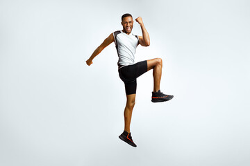 Number One. Full length portrait of excited black sportsman celebrating triumph jumping over red studio background