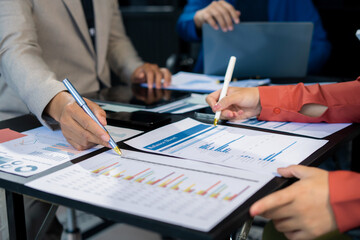 Business team using a calculator to calculate the numbers of statistic business profits growth rate on documents graph data, desk in the office.