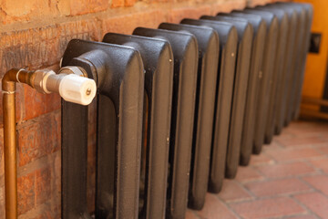 Classic metallic radiator installed in a cozy indoor space with exposed brick wall