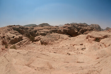 Fototapeta premium Exploring the ancient and rugged landscape of Petra, Jordan under a clear blue sky during midday sunlight