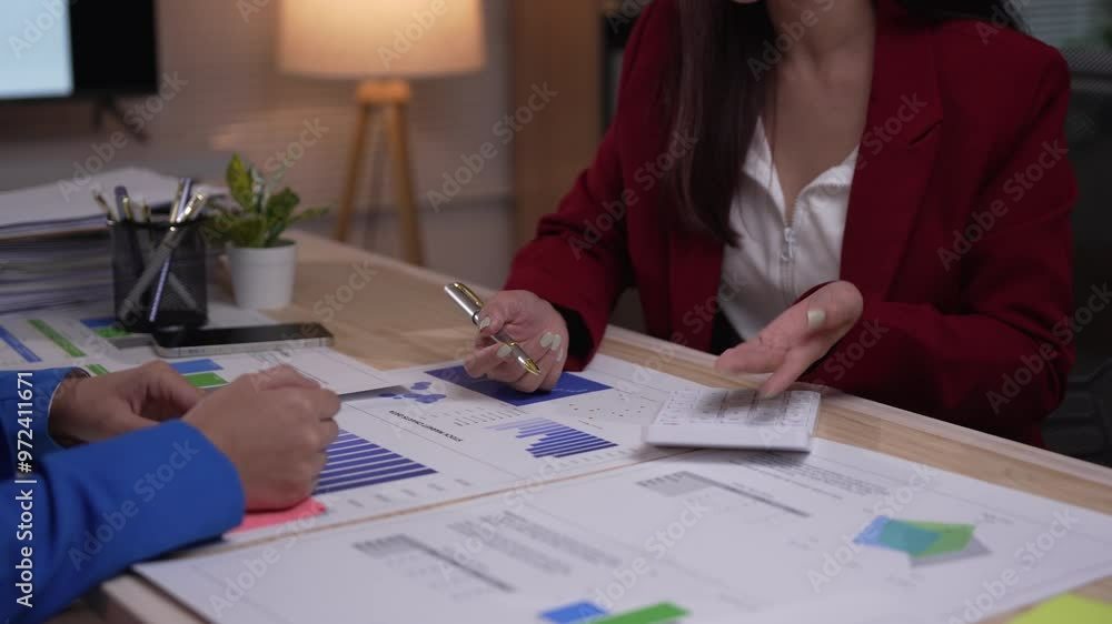 Aufkleber two businesswomen are sitting at a desk discussing a financial report. they are using a calculator a
