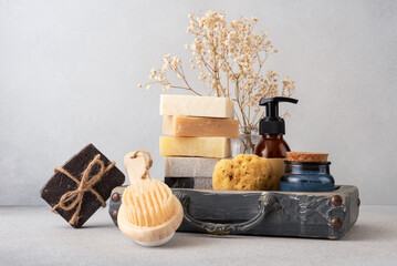 A beautifully arranged bathroom set featuring handmade soaps, a wooden back brush, and a natural sponge