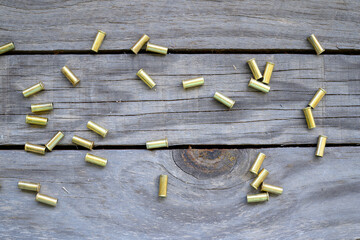 used spent bullet casings bullets on timber wooden bench, background backdrop, close closeup detail, ammunition shooting range rifle target 