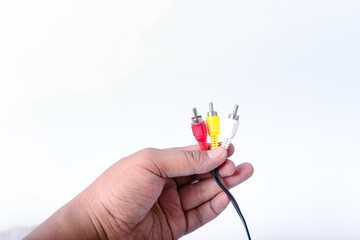 hand holding red, yellow and white RCA plugs with black cables isolated on white background.