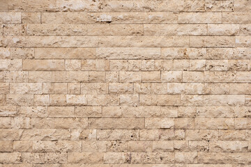 Textured beige stone wall with rectangular blocks in a modern architectural setting