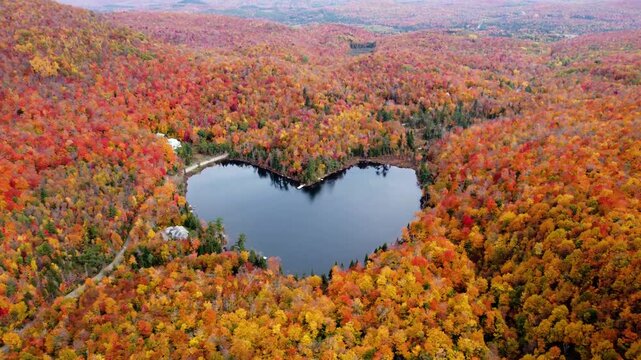 Aerial view of heart shape lake surrounded by autumn forest. Concept of earth day, love, environment, ecology. Baker Pond, Bolton-Est, Quebec, Canada.