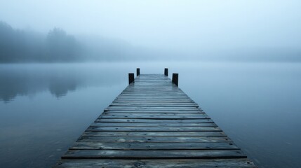 Obraz premium A wooden pier extending into a rain-covered lake, with mist and rain blurring the horizon