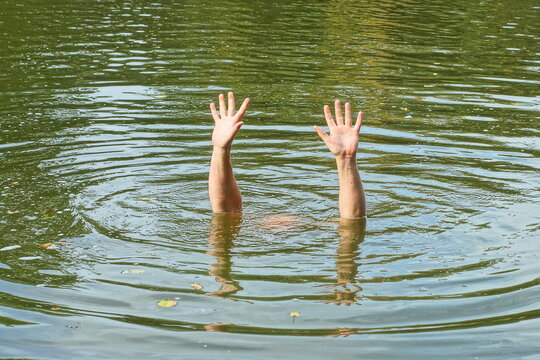 the risk of drowning a person in the river if he does not know how to swim. Two men's elbow-length hands peek out of the water in the summer afternoon on the lake and ask for help
